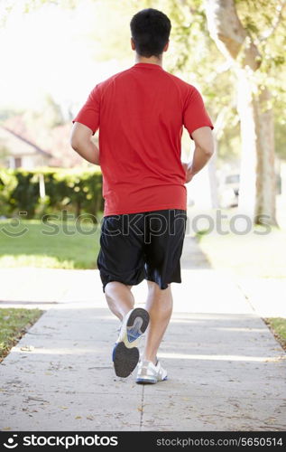 Rear View Of Male Runner Exercising On Suburban Street