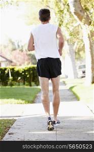 Rear View Of Male Runner Exercising On Suburban Street