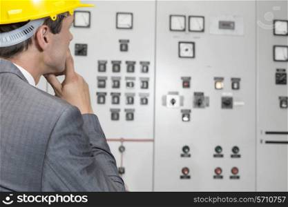 Rear view of male supervisor examining control room in industry