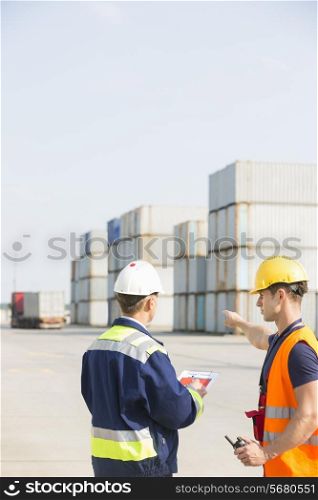 Rear view of male workers discussing in shipping yard