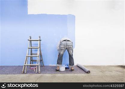 Rear view of man painting wall blue