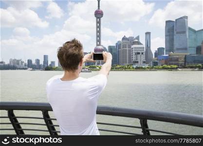 Rear view of man photographing Oriental Pearl Tower while standing by railing