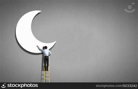 Rear view of man standing on ladder and reaching moon. Reaching the moon
