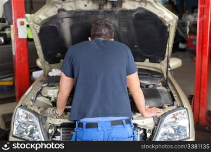 Rear view of mechanic working on a car in garage