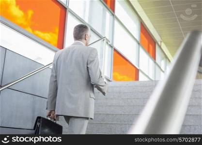 Rear view of middle aged businessman walking up stairs in railroad station