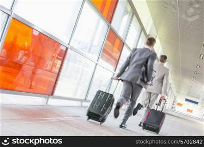 Rear view of middle aged businessmen with luggage rushing on railroad platform