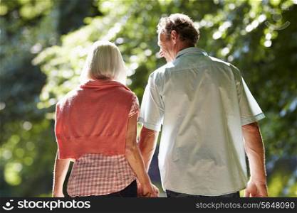 Rear View Of Middle Aged Couple Walking Along Country Lane