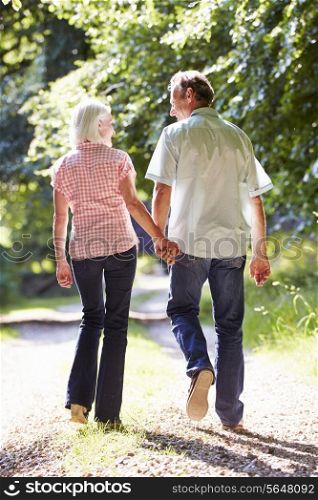 Rear View Of Middle Aged Couple Walking Along Country Lane