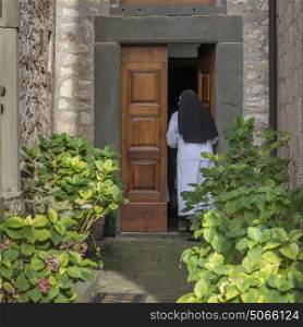 Rear view of nun entering in chapel, Radda in Chianti, Tuscany, Italy