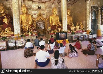 Rear view of pilgrims praying in a pagoda, Shwedagon Pagoda, Yangon, Myanmar