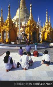 Rear view of pilgrims praying in front of a pagoda, Shwedagon Pagoda, Yangon, Myanmar