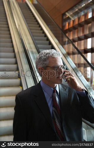 Rear view of prime adult Caucasian man in suit standing on escalator.