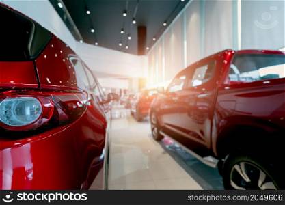 Rear view of red car parked in luxury showroom. Car dealership office. New car parked in modern showroom. Car for sale and rent business concept. Automobile leasing and insurance. Closeup tail light.