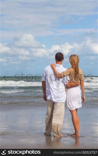 Rear view of romantic young man and woman couple embracing on a beach