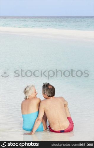 Rear View Of Senior Couple Sitting On Beautiful Beach
