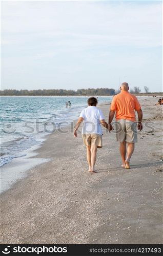 Rear view of senior couple walking on the beach.