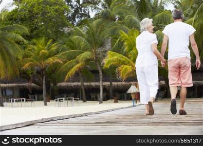 Rear View Of Senior Couple Walking On Wooden Jetty