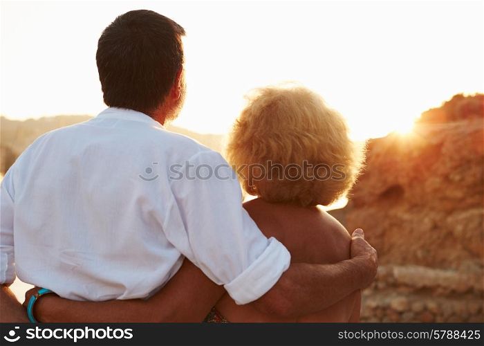 Rear View Of Senior Couple Watching Sunset Over Port