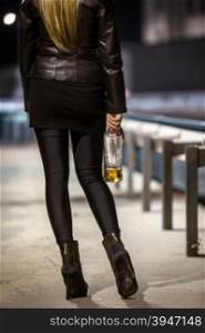 Rear view of sexy woman posing on street with bottle of whiskey