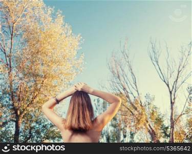 rear view of the blond haired women against trees with a lot of copyspace