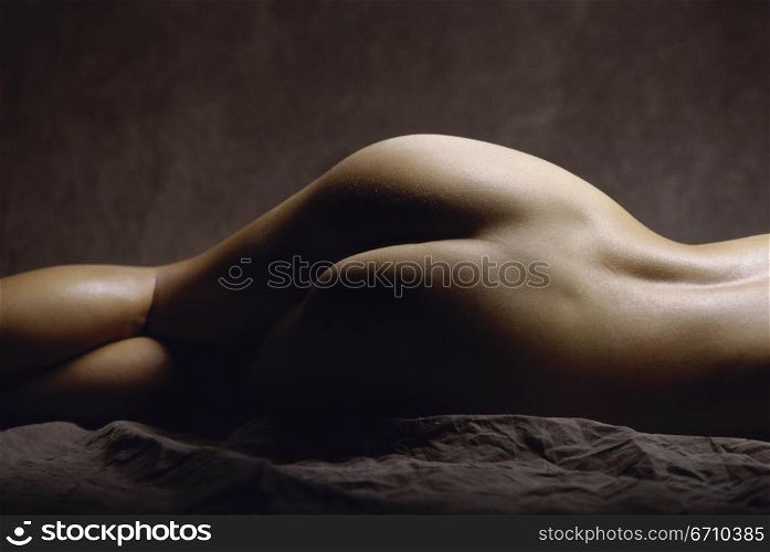 Rear view of the bottom of a naked young woman lying down