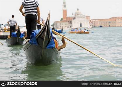 Rear view of three gondoliers rowing gondolas, Venice, Veneto, Italy