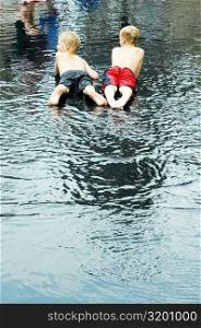Rear view of two boys lying down in water