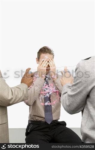 Rear view of two businessmen spraying a businessman with silly string