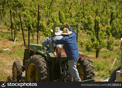 Rear view of two farmers on a tractor