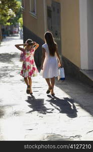 Rear view of two girls walking in a street, Capri, Campania, Italy