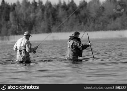 Rear view of two mature men fishing in the river