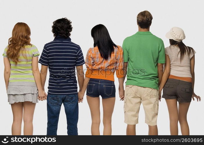 Rear view of two men and three young women standing with holding their hands