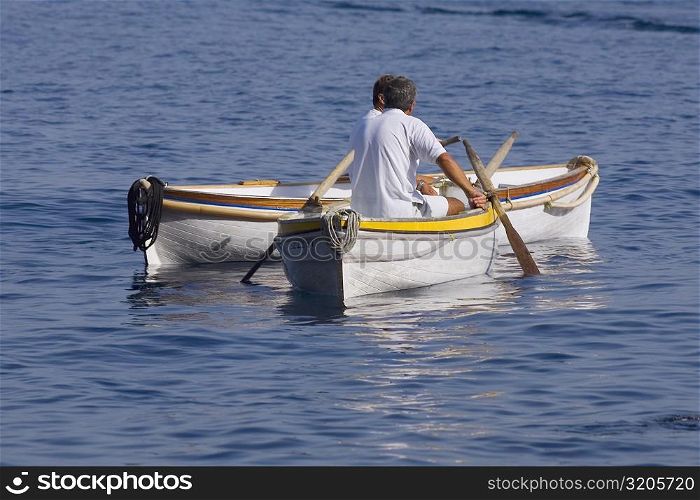 Rear view of two men sitting in boats, Capri, Campania, Italy