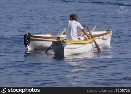 Rear view of two men sitting in boats, Capri, Campania, Italy