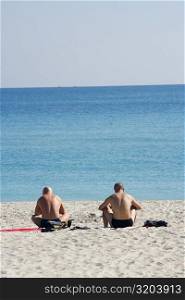 Rear view of two men sunbathing on the beach, Miami, Florida, USA