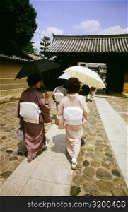 Rear view of two mid adult women walking on a walkway, Daitokuji Temple, Kyoto, Japan