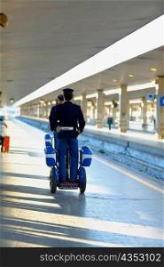 Rear view of two policemen traveling on scooters at a railroad station platform, Rome, Italy