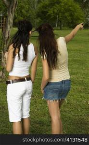 Rear view of two teenage girls standing in the garden