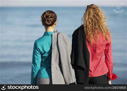 Rear view of two women standing on the beach