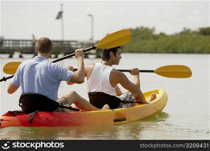 Rear view of two young men kayaking
