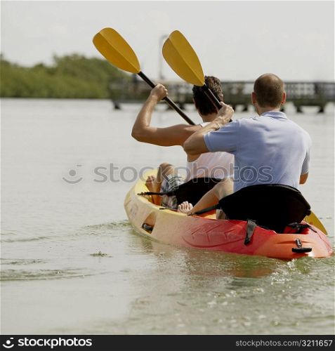 Rear view of two young men kayaking