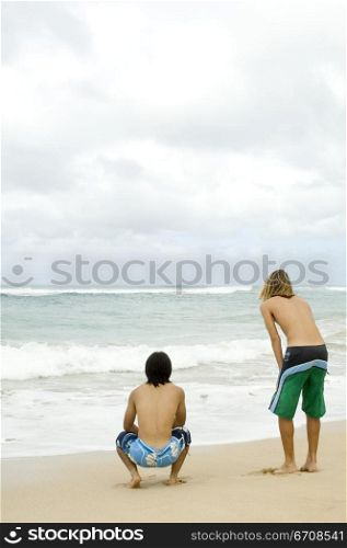 Rear view of two young men on the beach