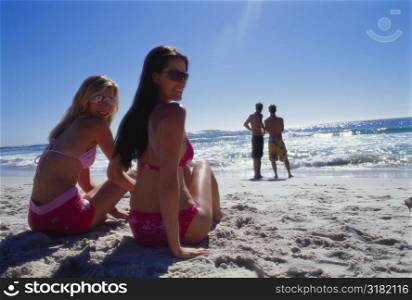 Rear view of two young women sitting on the beach