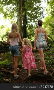 Rear view of two young women with a young girl (6-8) in a forest, Moorea, Tahiti, French Polynesia, South Pacific