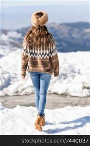 Rear view of woman enjoying the snowy mountains in winter, in Sierra Nevada, Granada, Spain. Female wearing winter clothes.. Young woman enjoying the snowy mountains in winter
