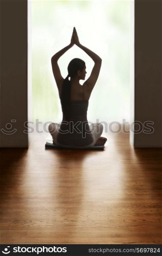 Rear view of woman meditating on floor