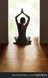 Rear view of woman meditating on floor