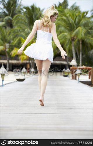 Rear View Of Woman Running Along Wooden Jetty
