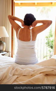 Rear View Of Woman Waking Up In Bed In Morning