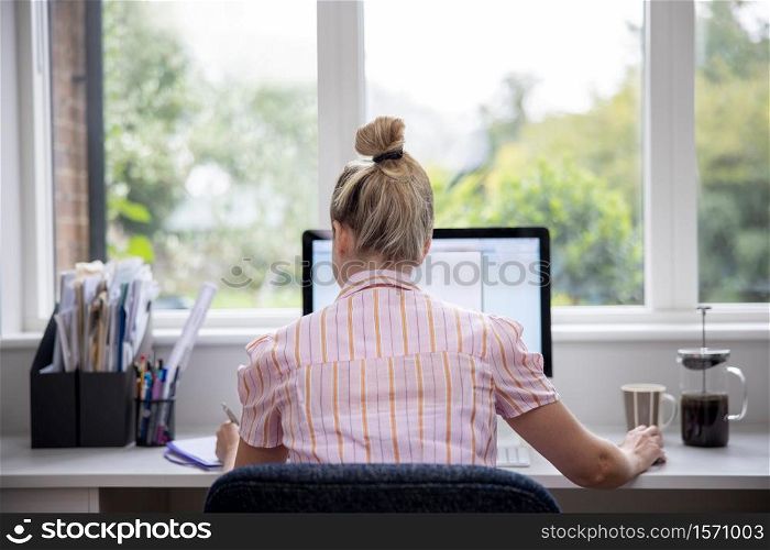 Rear View Of Woman Working From Home On Computer In Home Office